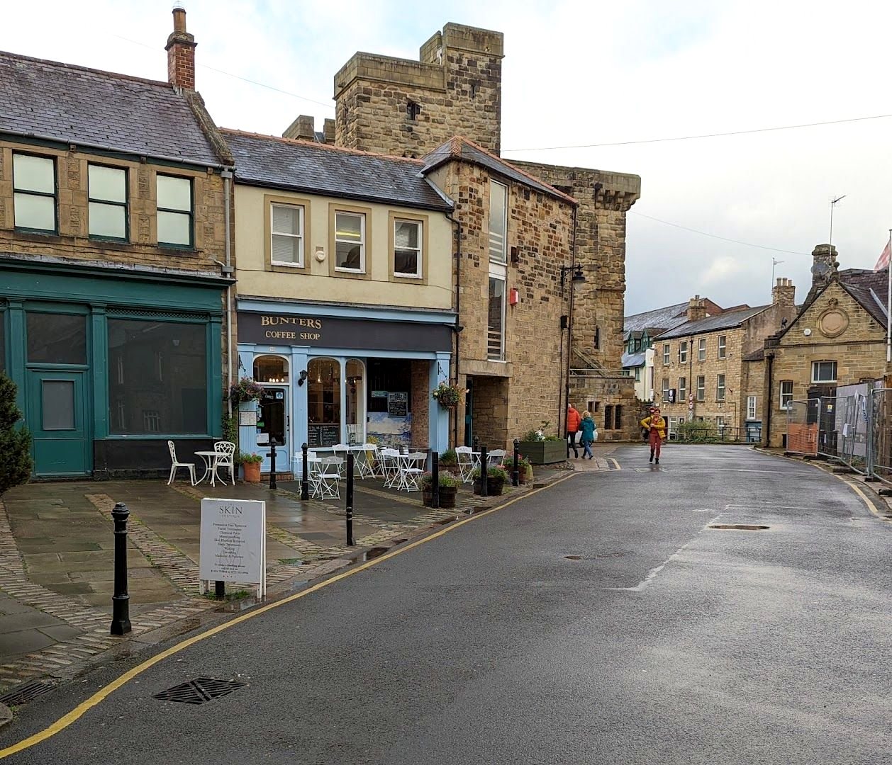 Hallgate in Hexham: the blue front of Bunters with tables outside, and the stone tower of the Old Gaol a few doors along